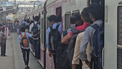 Passengers travelling on the footboard due to heavy crowd in the train.