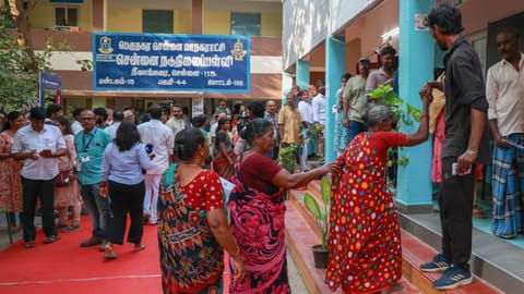 An elderly voter navigates the steps to cast her ballot in Neelankarai on Thursday