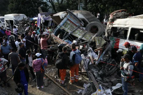People gather around vehicles damaged in an attack on the Pan-American Highway in Cajibio, Colombia, Saturday, April 25, 2026, that killed at least a dozen people and authorities blamed on dissident groups of the former FARC rebels.