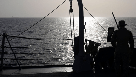 A US Sailor watches a commercial vessel as American forces continue to enforce a blockade against Iranian ports