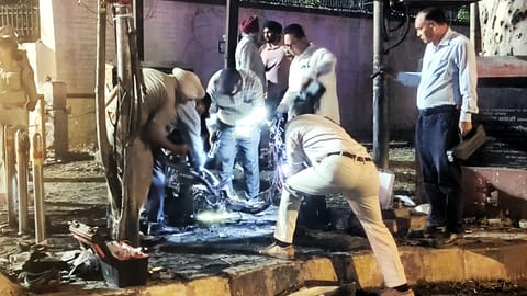 Security personnel inspect the remains of a scooter after a fire incident near the BSF headquarters, in Jalandhar