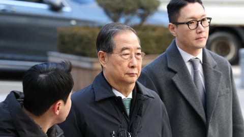 Former South Korean Prime Minister Han Duck-soo, center, arrives at the Seoul Central District Court for his first sentencing trial in the insurrection case, in Seoul