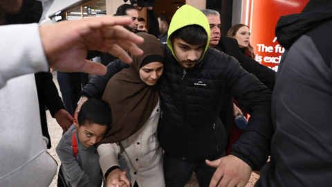 A group of supporters surround a woman and child with alleged ties to the Islamic State as they arrive at Melbourne international Airport, in Melbourne, Australia, Thursday, May 7, 2026.
