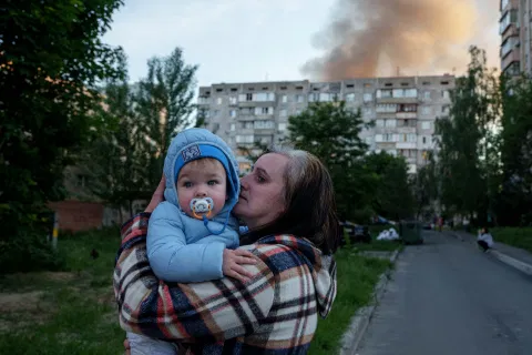 A woman carries a baby near a residential house damaged after a Russian strike in Kyiv, Ukraine, on Tuesday, June 2, 2026