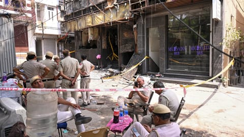 Police personnel investigate the spot a day after a fire at the Flourish Stay B&B killed at least 21 people, including 12 foreigners
