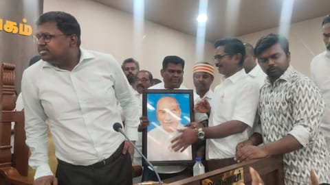 Congress councillor R Stephen Babu carries a portrait of former Chief Minister K Kamaraj, urging for its installation at the council meeting in Karur on Monday