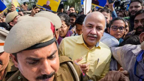 Delhi Police personnel escort Manish Sisodia from Rajghat ahead of his questioning by CBI