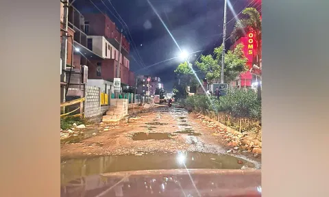 The unlaid road full of potholes and stagnated rainwater poses safety risk for commuters