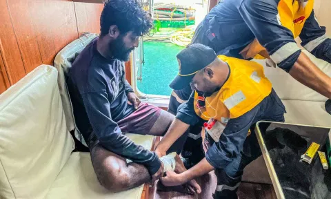 A Coast Guard personnel treating an injured fisherman