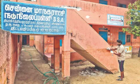 A staff of the school cleaning the oil stain from the wall.