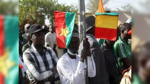 A man holds Mali and Burkina Faso flags while attending a sit-in in Niamey (Photo:Reuters)