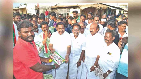 Edappadi K Palaniswami gives away a campaign pamphlet to a voter at Mattuthavani vegetable market in Madurai