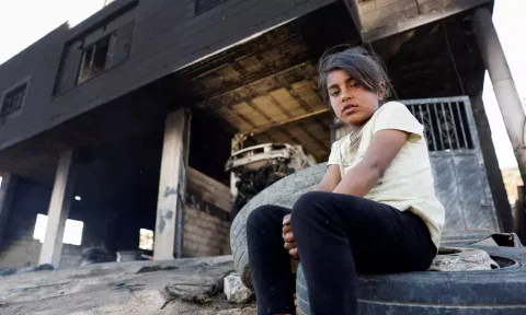  A Palestinian girl sits in front of her house after Israeli settlers attacked the village of al-Mughayyer, in the Israeli-occupied West Bank (Reuters)