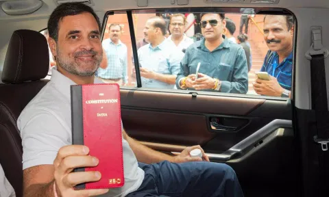 Congress member Rahul Gandhi shows a book of Constitution of India at the Parliament House complex (PTI)