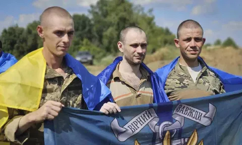 Ukrainian prisoners of war hold Marine's flag as they pose for a photo after a prisoners exchange at an undisclosed location in Ukraine. (AP)