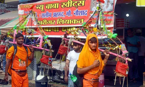  Kanwariyas walk past a shop on which banners with shopkeeper's name was put up on Kanwar Marg after an order issued by Uttar Pradesh Government (PTI)