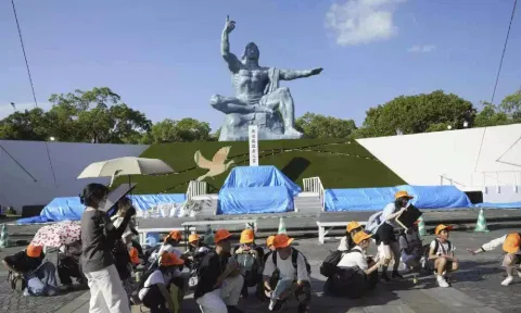 Visitors to the Peace Park crouch as an earthquake alert was issued in Nagasaki, western Japan (AP)