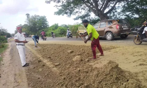  Under the presence of the police, a few locals shovelled the sand from the road 