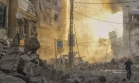 Man runs for cover as a smoke raises in the background following an Israeli airstrike in Dahiyeh, Beirut, Lebanon (AP)