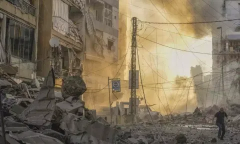 A man runs for cover as a smoke raises in the background following an Israeli airstrike in Dahiyeh, Beirut, Lebanon (AP)