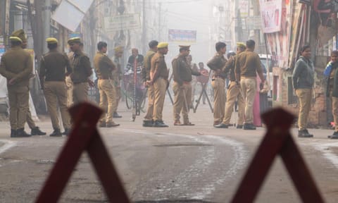 A security personnel stands guard as voters wait in queues to cast votes at a polling booth during the Kedarnath Assembly constituency bypoll, in Rudraprayag (PTI) 