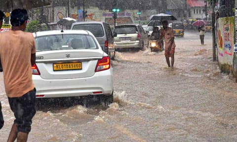 Commuters wade through a waterlogged road amid rains, in Thiruvananthapuram (PTI)