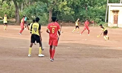 Young boys playing hockey on gravel pitch at Vadipatti 