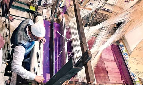 A handloom weaver in Varanasi crafting intricate designs on a traditional silk saree 
