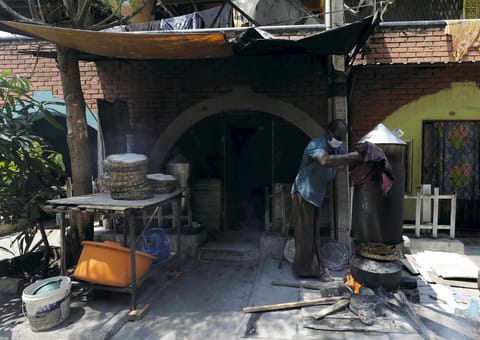 A man who runs a home based food business uses a traditional Sri Lankan wooden stove