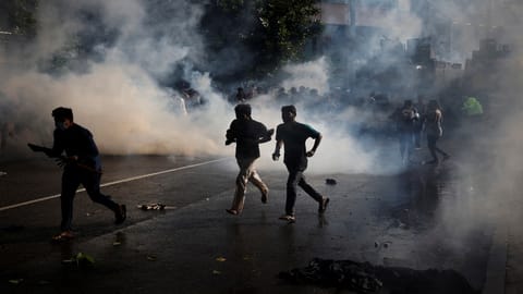 Protestors run for cover as police use tear gas during a protest