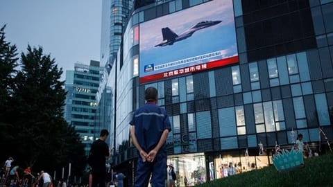 A man watches a CCTV news broadcast, showing a fighter jet during joint military operations near Taiwan by the Chinese's PLA, at a shopping center in Beijing