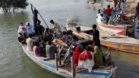 Residents use boats to transport their belongings as they head to their village, following rains and floods during the monsoon season in Sehwan, Pakistan