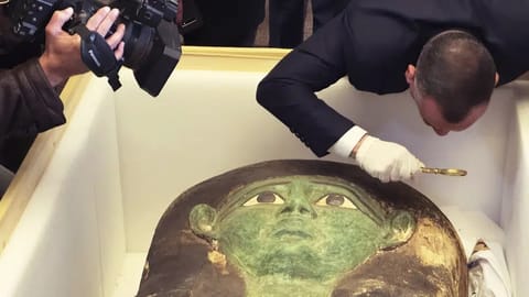Mostafa Waziri, top official at the Supreme Council of Antiquities, takes a look with a magnifier at an ancient wooden sarcophagus during a handover ceremony at the foreign ministry in Cairo, Egypt.