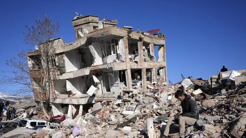A man sits at his destroyed house in Kahramanmaras, southern Turkey.