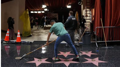 A worker sweeps away rainwater from the Walk of Fame during preparations for Sunday's 95th Academy Awards.