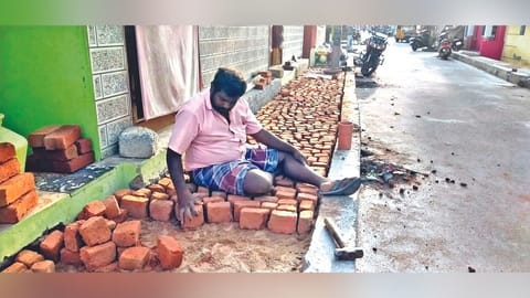 A resident of Vijayaraghavapuram filling the half done pavement
with bricks and concrete mix in Sathuvachary, Vellore.
