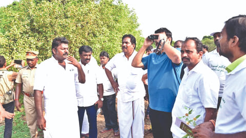 Minister M Mathiventhan using a binocular to view a biodiversity spot at Idayapatti in Madurai on Sunday