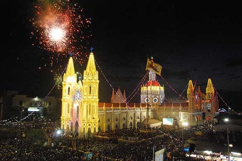 Holy flag hoisted, with aerial fireworks in the background, at the Velankanni basilica