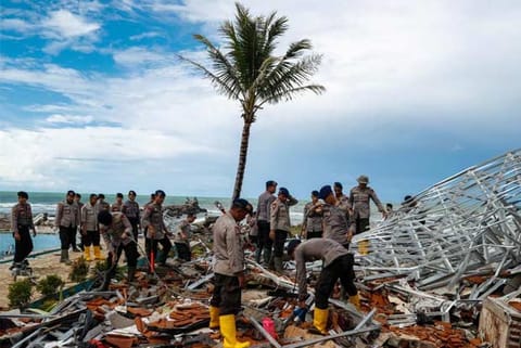 Police officers search for victims among rubble of a tsunami-hit beach front hotel