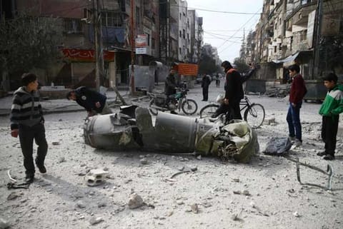 People inspect missile remains in the besieged town of Douma