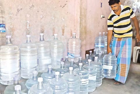 A supplier of treated water cans arranges his stock