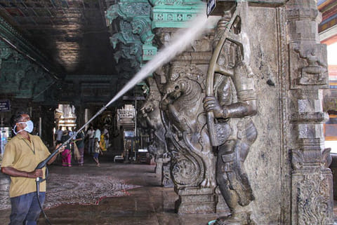 A worker sprays disinfectant within the premises of Meenakshi Amman Temple in Madurai
