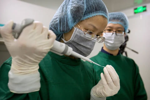 Chinese scientists load Cas9 protein and PCSK9 sgRNA molecules into a fine glass pipette at a lab