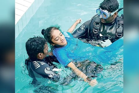 Differently abled individuals in swimming pool with assistants