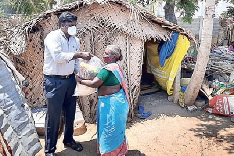 A volunteer gives a packet of essentials to a labourer
