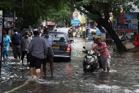 People wading through a flooded road (Image credit: Manivasagan)