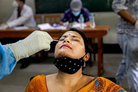 An health worker takes a nasal swab sample of a teacher to test for Covid-19 (Credit: AP)