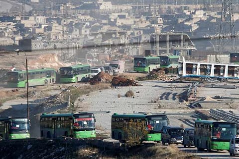 Ambulances and buses evacuating people drive out of a rebel-held part of Aleppo