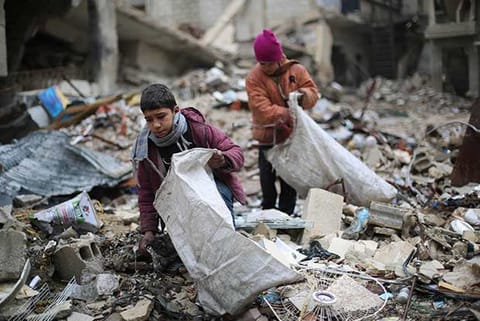 Syrian youths collect wood from rubble to be used for heating and cooking
