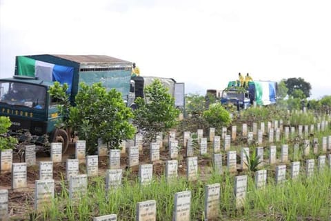 Trucks convey the remains of mudslide victims for burial at the Paloko cemetery